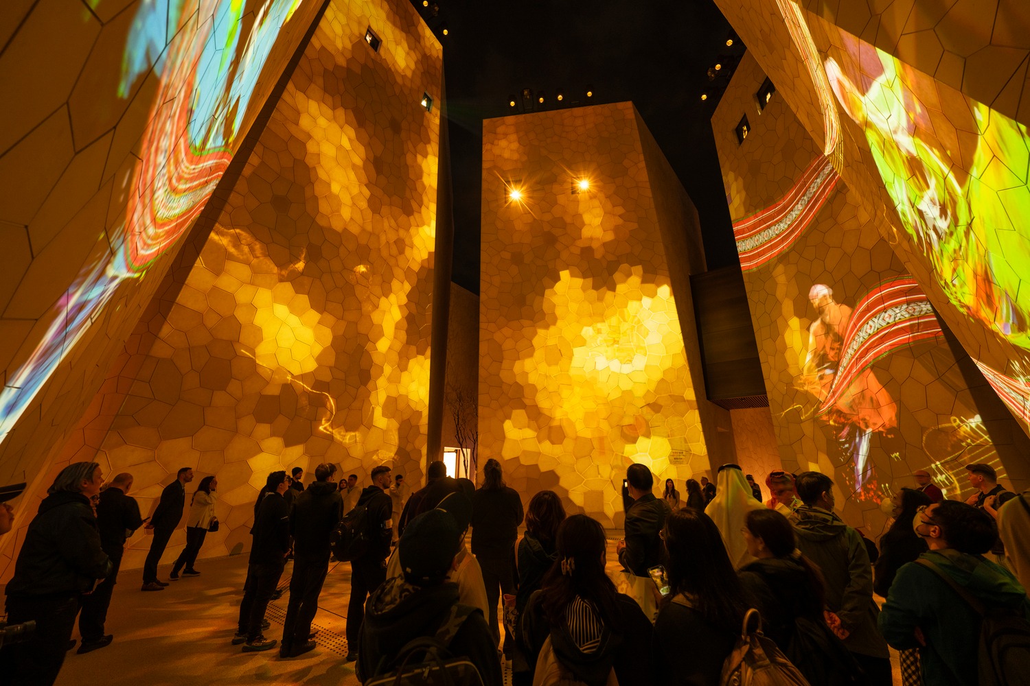 Visitors surrounded by illuminated walls and projections in the Saudi Arabia Pavilion